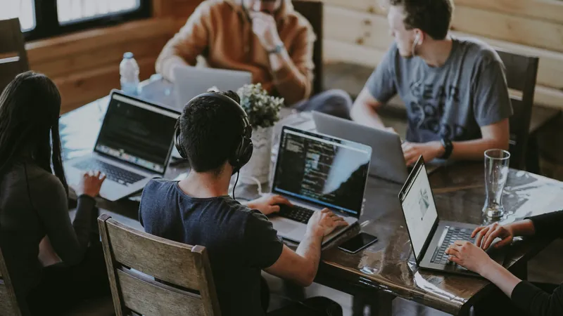 Team arbeitet gemeinsam an Laptops im Büro — Meeting-Transkription und Datenschutz bei Koreva eG
